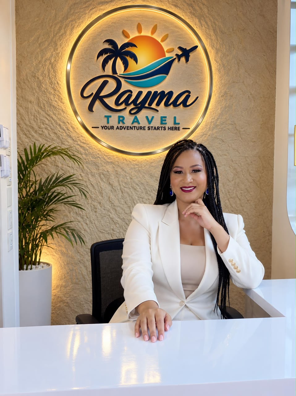 Rayma at the front desk of her office, under the Rayma Travel sign