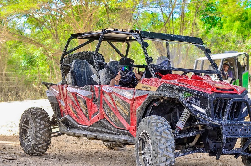 A red buggy with its riders, in helmets and face scarves