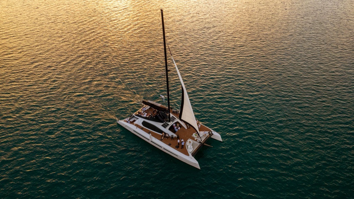 A catamaran sailing at sunset, seen from above