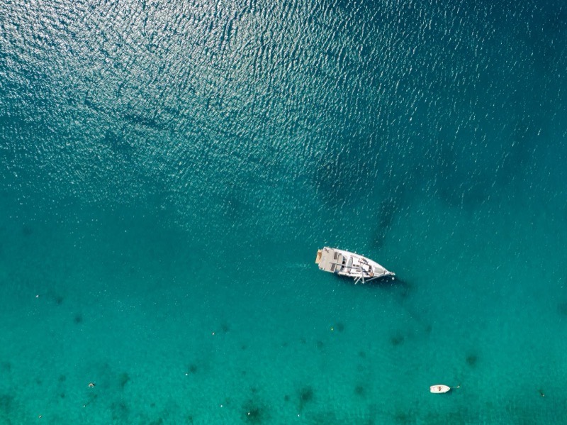 A yacht anchored in turquoise water, seen from above