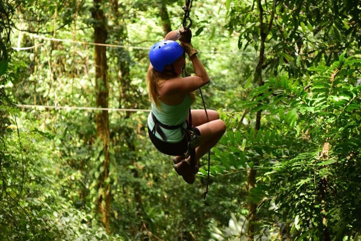 A woman riding a zip line through the greenery