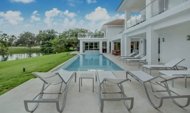 The long pool with sun loungers and lawn down to the lake