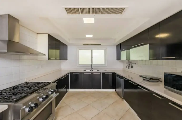 A kitchen with an island, extractor hood and dark worktops