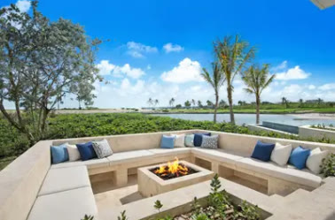 A circular sofa around a fire pit, beside the water