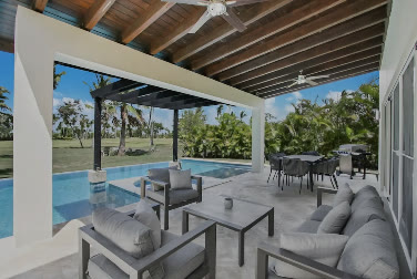 A covered terrace with sofas beside the pool