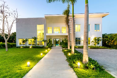 The villa lit at night from the entrance path