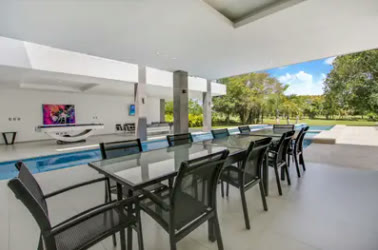 An outdoor dining area with a long table by the pool