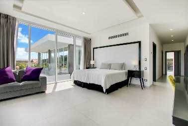A bedroom with a dark headboard opening onto the garden