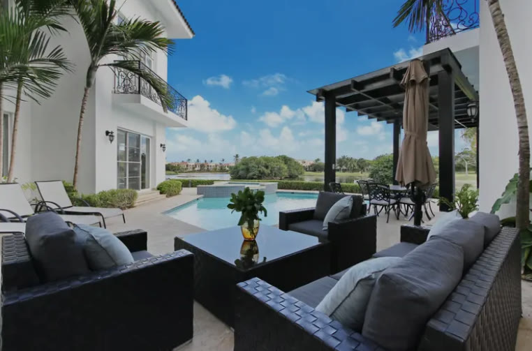 A terrace with sofas and a pergola beside the pool