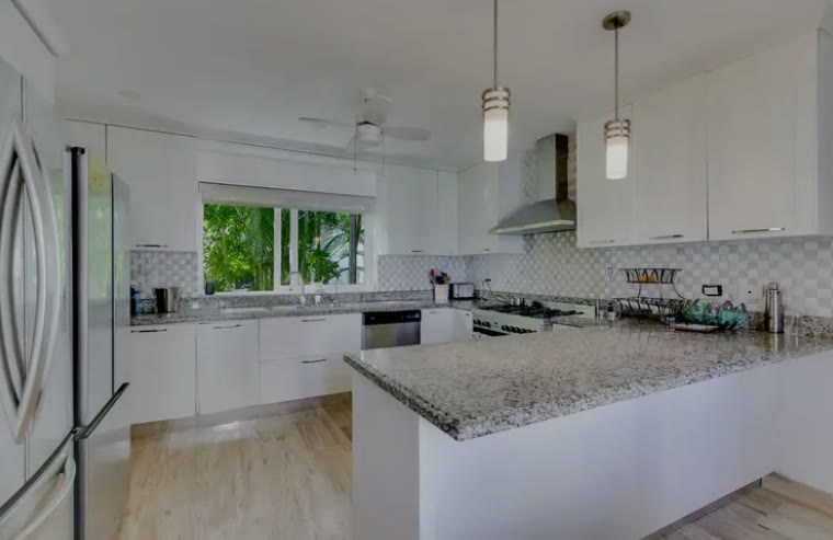 A white kitchen with a granite island