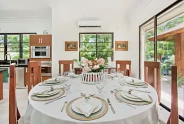 A dining room with a laid round table and the kitchen behind