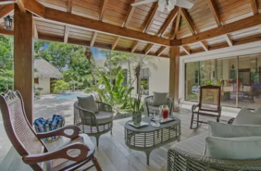 A wooden gazebo with armchairs beside the pool